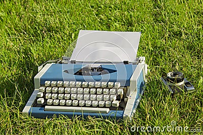 Typewriter and old camera in the grass Stock Photo